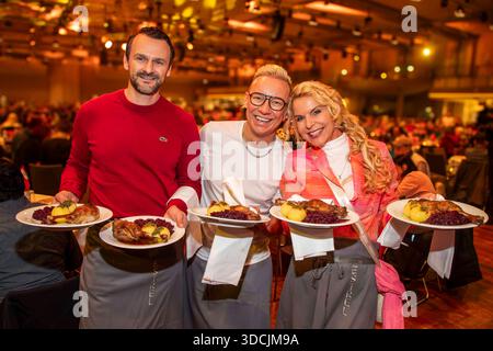 abb: David Biethig, Sascha Lauterbach und Victoria Herrmann als Promi Kellner beim Servieren von Teller mit Gaensekeuele Rotkohl und Kloesse bei der 31. Frank Zander Weihnachtsfeier Weihnachtsessen fuer Obdachlose und Beduerftige Menschen 2025 im Estrel Convention Center AM 22.12.2025 a Berlin Berlin Berlin Deutschland Foto Stock
