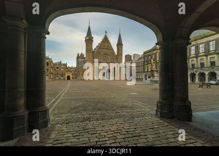 Vista del maestoso castello di Binnenhof con le sue guglie gotiche che perforano il cielo, incorniciato da archi in pietra a l'Aia, l'Aia, Paesi Bassi. Foto Stock