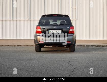 Vista posteriore del SUV nero parcheggiato vicino a una parete bianca. Black KIA Sorento in una strada vicino ad alcuni edifici commerciali o industriali. Foto Stock