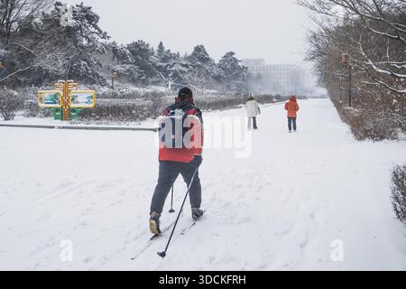Changchun, la provincia cinese di Jilin. 23 dicembre 2025. Un uomo che indossa un paio di sci è raffigurato per strada in mezzo alla neve a Changchun, nella provincia di Jilin, nel nord-est della Cina, il 23 dicembre 2025. Il martedì a Changchun si sono verificate nevicate a causa dell'impatto di un nuovo fronte freddo. Crediti: Xu Chang/Xinhua/Alamy Live News Foto Stock