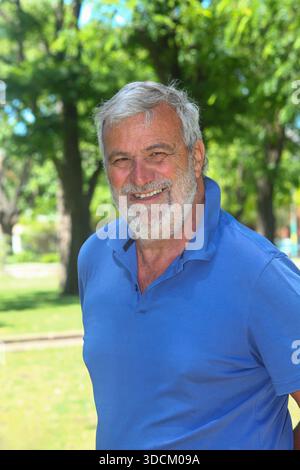 Ritratto di un allegro anziano latinoamericano sorridente all'aperto con vegetazione lussureggiante sullo sfondo. Foto Stock
