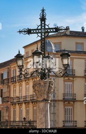 Primo piano di un monumentale lampione di ferro su una capitale classica con edifici e cupole tradizionali nel centro storico di Malaga Foto Stock