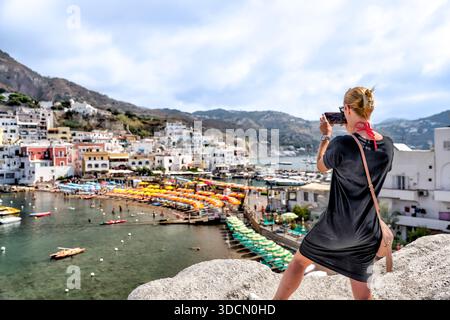Visitatore che fotografa il porto e gli ombrelloni del villaggio di Sant'Angelo da un punto di vista sopraelevato, Ischia, Campania, Italia. Foto Stock