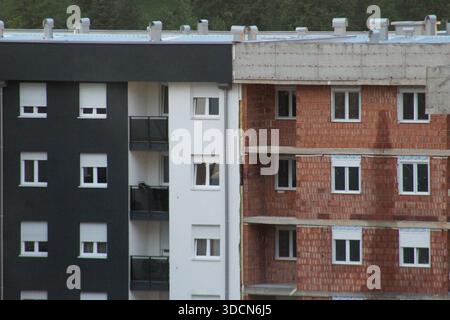 L'esterno dei vicini edifici residenziali mostra una facciata moderna rifinita accanto ad una struttura in mattoni incompiuta. Foto Stock