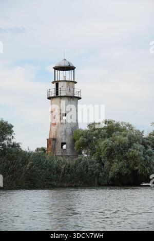 Viaggia in romania, tulcea sulina, delta del danubio, faro di sulina, un'antica struttura di navigazione, in piedi vicino all'acqua e alla vegetazione Foto Stock