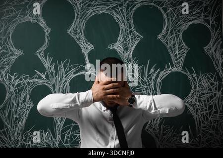 Uomo d'affari depresso vicino a teste disegnate sulla lavagna. Settimana internazionale di sensibilizzazione sullo stress Foto Stock