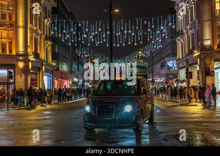 Oxford Circus Christmas Lights, London taxi in the December rain, Oxford Street, Londra, Inghilterra, Regno Unito. Inverno. Scena notturna. Foto Stock