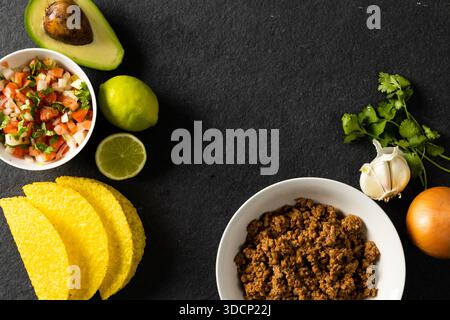 Direttamente sopra il colpo di tortilla, carne, avocado, limone, coriandolo, cipolla, pomodoro e aglio sul tavolo Foto Stock