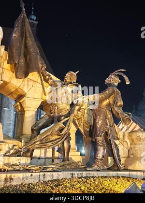 Gruppo di statue di Matthias Corvinus a Cluj-Napoca illuminate di notte, luci invernali festose, monumento storico nel centro della città Foto Stock