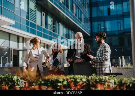 I colleghi di lavoro discutono i documenti all'esterno di un moderno edificio per uffici durante le pause diurne Foto Stock