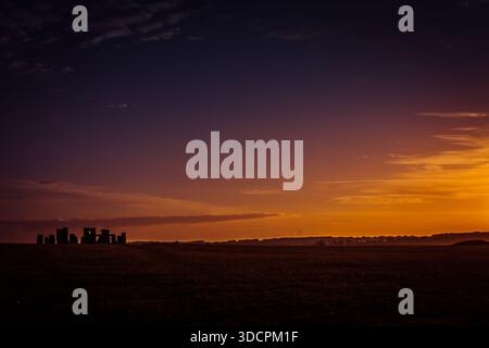 Sagoma del cerchio di pietre di Stonehenge contro una vivace alba arancione sulla piana di Salisbury, Wiltshire, Inghilterra. Foto Stock