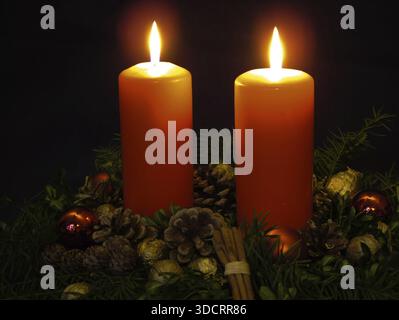 Corona d'avvento festiva con due candele accese, coni di pino, coni di pino, rami di pino, bastoncini di cannella, palle di Natale e noci dorate, noci, Chri Foto Stock