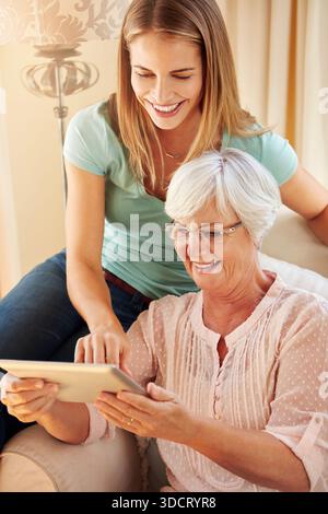 Donna anziana, tablet e figlia adulta sul divano, sorridere e insegnare con tecnologia, occhiali e cura a casa. Madre anziana, imparare e scorrere con Foto Stock