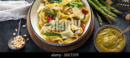 Fituccine con pesto di basilico e pinoli su un piatto bianco. Fituccine al pesto secondo una tradizionale ricetta italiana su un backgroun scuro Foto Stock