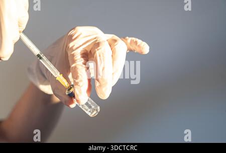 Operatore sanitario che prepara la siringa con il flaconcino di vaccino Foto Stock