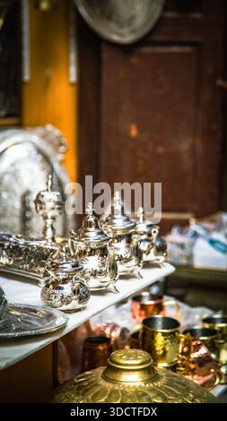 Artigianato marocchino a Fez: Teiere, vassoi, coperchi dorati e tazze di rame finemente incise in un negozio tradizionale. Foto Stock