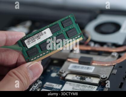 Primo piano di una mano che tiene in mano un modulo di memoria, con l'etichetta FRU (Field Replaceable Unit, unità sostituibile sul campo). Utile per argomenti sulla compatibilità delle parti e l'autenticità h Foto Stock