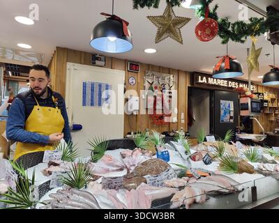 Pescivendolo che vende una varietà di pesce fresco e frutti di mare sul ghiaccio, Les Halles de Pau, Pyrénées Atantiques, Francia Foto Stock