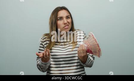 Donna che tiene in mano banconote della corona islandese con un'espressione riflessiva su sfondo bianco isolato, suggerendo decisioni finanziarie o denaro ma Foto Stock