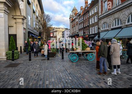 Scena festiva al Covent Garden di Londra il 24 dicembre 2025, con folle di persone che camminano e si godono il mercatino di Natale. Foto Stock
