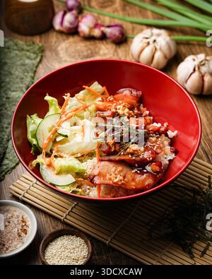 Una vivace e appetitosa ciotola per riso di pollo teriyaki, con un morbido pollo glassato, un soffice riso bianco, lattuga croccante, carote tritate e cetriolo Foto Stock