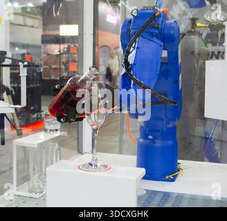 Manipolatori robotici. Robot che versa la bevanda liquida dalla bottiglia al bicchiere. Robot industriale. Mano del braccio del robot. Manipolatori industriali per saldature di vario tipo Foto Stock
