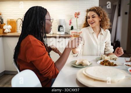 Amici diversi che mangiano e parlano in cucina Foto Stock