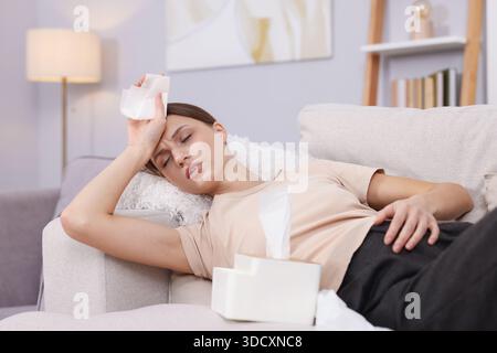 Donna incinta con tessuti che soffrono di febbre sul divano a casa. Sintomo freddo Foto Stock