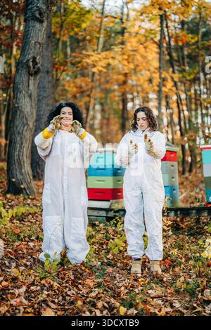 Donne apicoltori che indossano abiti protettivi che lavorano con gli alveari Foto Stock