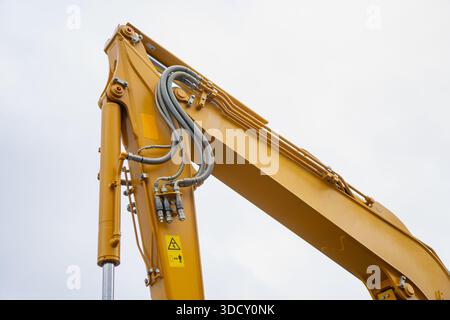 Il braccio dell'escavatore industriale e il braccio idraulico mostrano i tubi flessibili, i giunti e i componenti dei cilindri, che rappresentano il design delle moderne attrezzature per l'edilizia Foto Stock