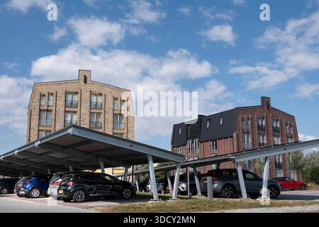 Le auto sono parcheggiate sotto una tettoia con pannelli solari in un nuovo condominio. Energia sostenibile e ombra allo stesso tempo Foto Stock