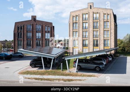 Le auto sono parcheggiate sotto una tettoia con pannelli solari in un nuovo condominio. Energia sostenibile e ombra allo stesso tempo Foto Stock