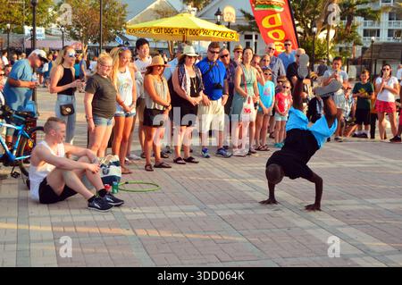 Un artista di strada attira una folla che esegue ginnastica e stimolanti mosse di danza a Mallory Square a Key West, Florida Foto Stock