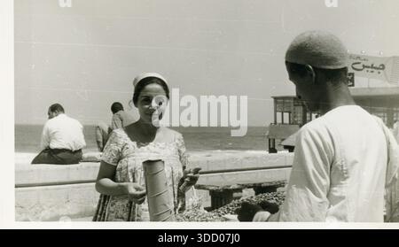 Donna egiziana che acquista frutta da un venditore ambulante sul lungomare di Alexandria Corniche, Egitto, anni 1950-1960 Foto Stock
