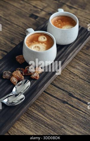 Due tazze di caffè su vassoio di legno con primo piano di zucchero di canna Foto Stock