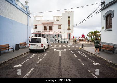 ICOD DE LOS VINOS, SPAGNA - 2 AGOSTO 2025: Strada con auto parcheggiate e pedoni vicino all'edificio del negozio di souvenir e alla passerella. Tenerife, Isole Canarie Foto Stock