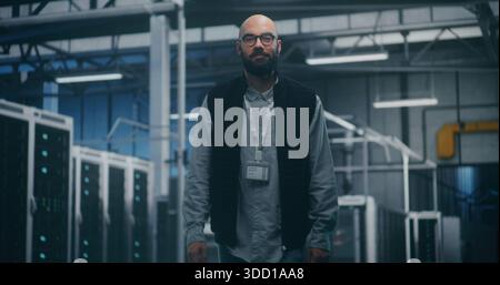 Specialista di audit interno che ispeziona le apparecchiature nello spazio dei server industriali. Man in abito professionale esegue audit mentre cammina tra le unità server. Analisi del sistema concettuale, ispezione tecnica. Foto Stock