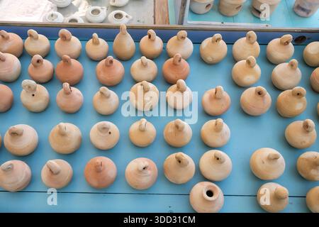 Vista ad angolo elevato di molte piccole lampade a olio di argilla fatte a mano e brocche disposte in file su una superficie blu. Foto Stock
