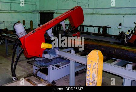Sega a nastro orizzontale industriale che taglia grandi tubi in acciaio in officina Foto Stock