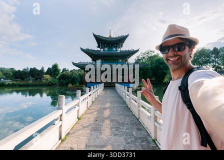 Un ragazzo fa un selfie in un tempio in stile cinese. Un adolescente europeo in viaggio in Cina. Foto Stock