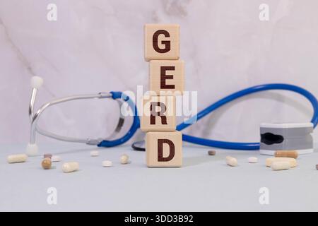 La parola GERD è scritta su un blocco di legno con stetoscopio, siringa e pillole. Concetto medico Foto Stock