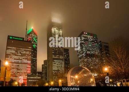 Grattacieli, tra cui Two Prudential Plaza e l'Aon Center, avvolti da una nebbia bassa luminosa e dalla foschia notturna sopra il Millennium Park. Foto Stock