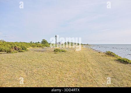 Paesaggio costiero roccioso con ex posto di guardia di frontiera sovietico o torre di guardia e edificio sullo sfondo in estate, Türju, Saaremaa, Estonia. Foto Stock