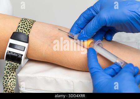 Primo piano di un operatore sanitario che indossa guanti pronti a prelevare un campione di sangue dalla vena del braccio con una provetta Vacutainer durante la procedura di venepuntura Foto Stock