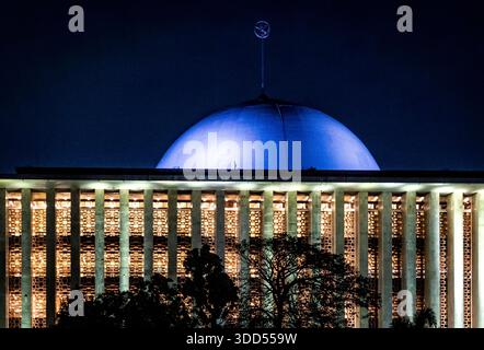 Cupola illuminata di un edificio moderno di notte con alberi in primo piano. Foto Stock