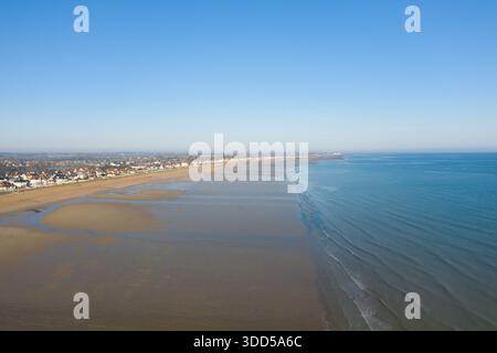 L'ampia vista aerea di Sword Beach a Hermanville-sur-Mer rivela un'ampia sabbia bagnata e dolci onde, con una lunga fila di case che confinano con la tranquilla costa sotto un cielo azzurro. Foto Stock