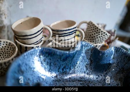 Tazze di ceramica fatte a mano con strisce blu e punti, insieme a una grande ciotola smaltata blu, esposte in uno studio di ceramica a Nazareth. Foto Stock