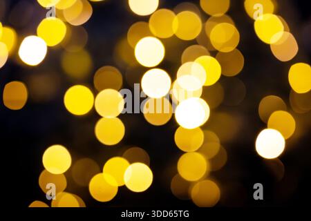 Luci di Natale gialle lampeggianti e bokeh dalla sfocatura. Sfondo scuro. Foto Stock