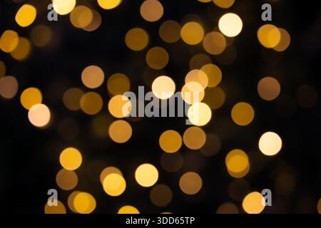 Luci di Natale gialle lampeggianti e bokeh dalla sfocatura. Sfondo scuro. Foto Stock