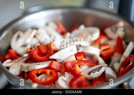 Primo piano di funghi tritati e peperoni colorati saltati in una teglia calda Foto Stock